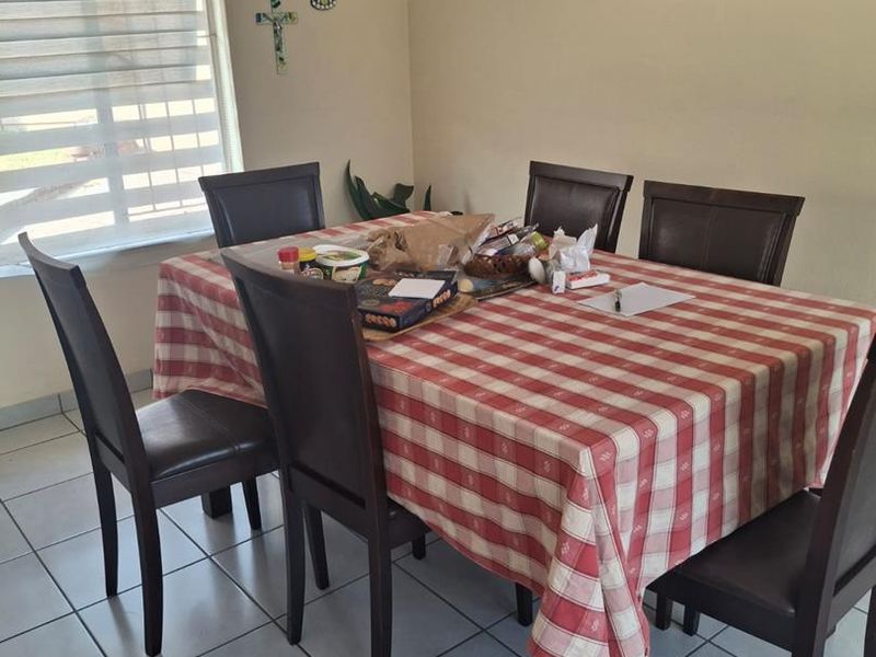 A functional dining area featuring neutral walls, tiled flooring, and a window fitted with modern roller blinds.