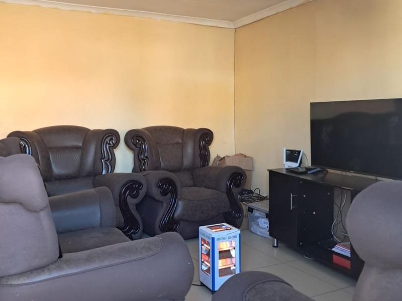 A living room featuring tiled flooring and plain walls, currently showing signs of wear and requiring cosmetic updates to the ceiling and wall finishes.
