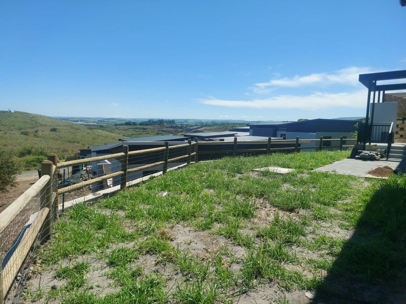 Rear outdoor area featuring a timber fence, concrete patio, and pergola structure with expansive views of the surrounding landscape.