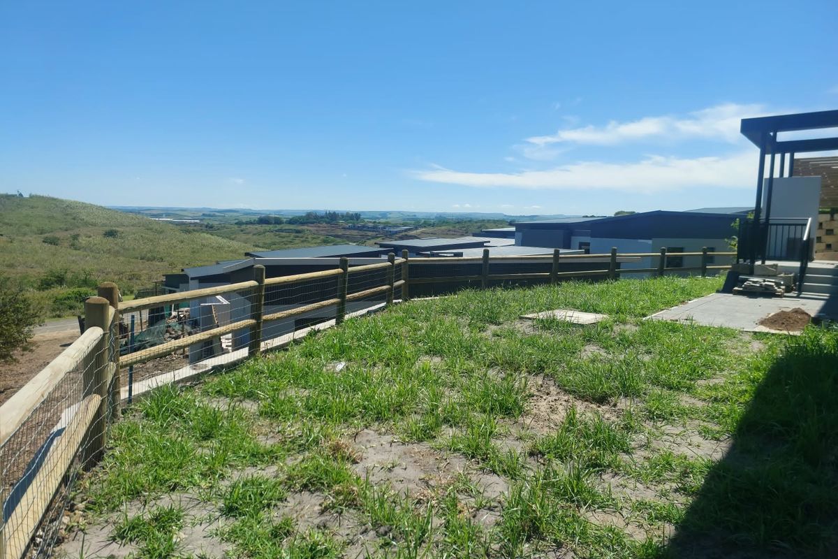 Rear outdoor area featuring a timber fence, concrete patio, and pergola structure with expansive views of the surrounding landscape.