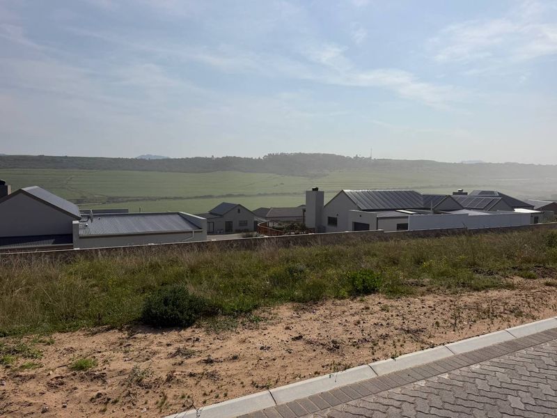 A view from the vacant residential plot overlooking the surrounding estate and distant rolling hills.