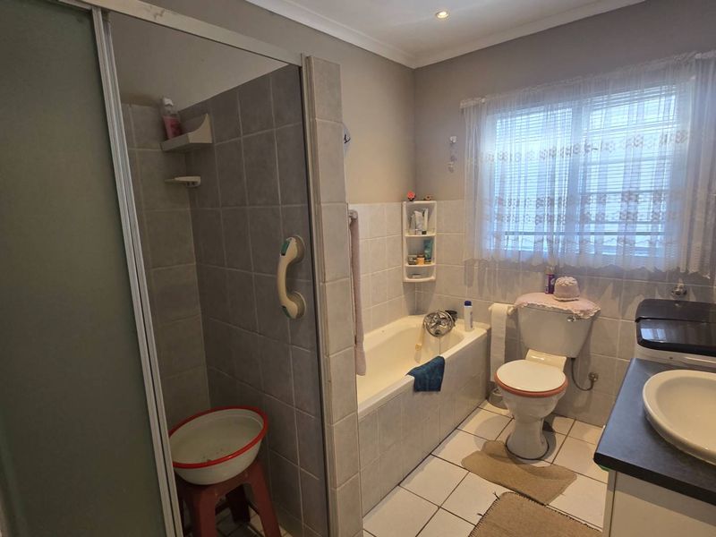 A functional bathroom featuring a separate shower enclosure, built-in bathtub, toilet, and a vanity basin with tiled finishes throughout.