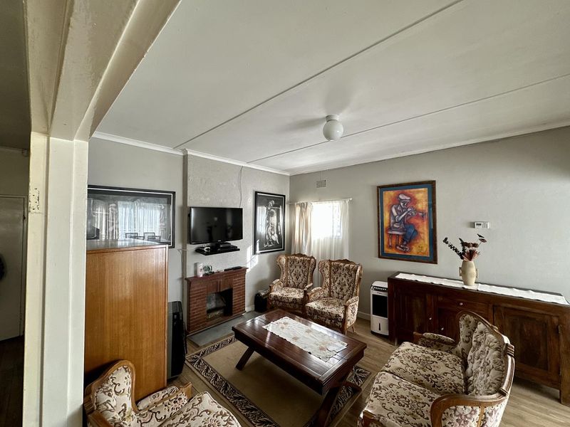A living room featuring a brick fireplace, laminate flooring, and neutral wall finishes, offering a functional space with potential for modernization.