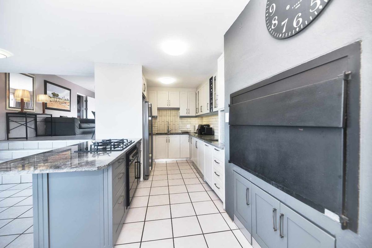 Modern kitchen featuring a central island with a built-in gas hob, stone countertops, and integrated cabinetry, seamlessly flowing into the adjacent living area.