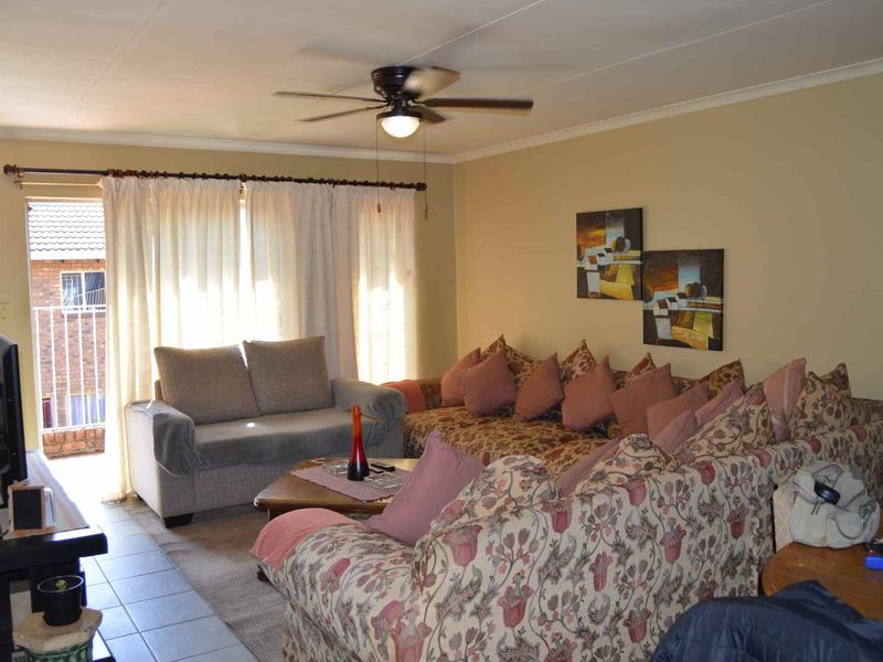 A living room featuring tiled flooring, a ceiling fan, and a sliding glass door providing access to an outdoor balcony area.
