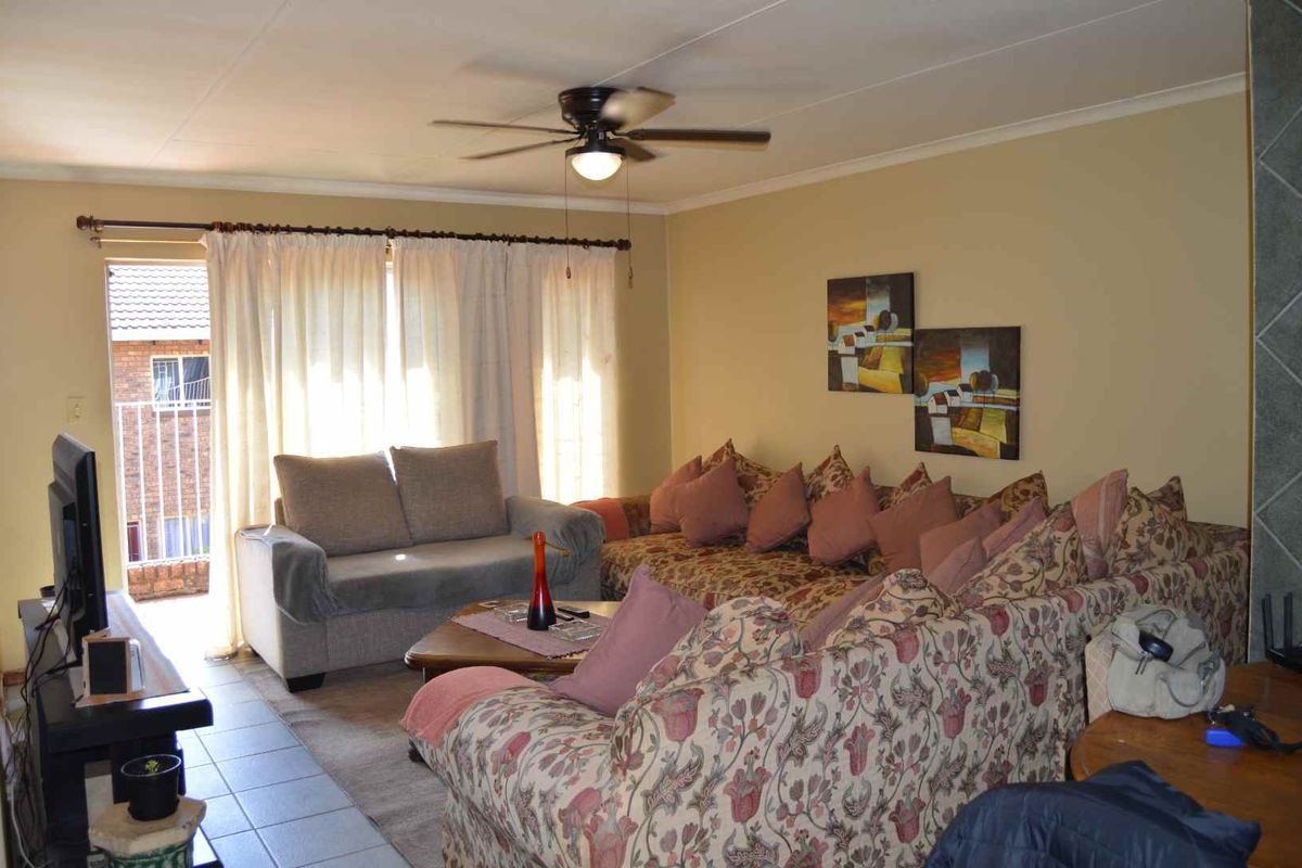 A living room featuring tiled flooring, a ceiling fan, and a sliding glass door providing access to an outdoor balcony area.