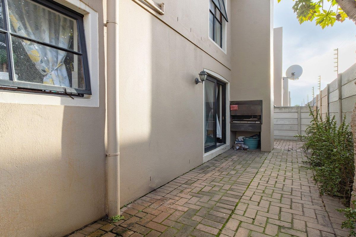 Rear exterior area featuring a paved patio, built-in braai, and perimeter walling, offering a functional outdoor space for entertaining.