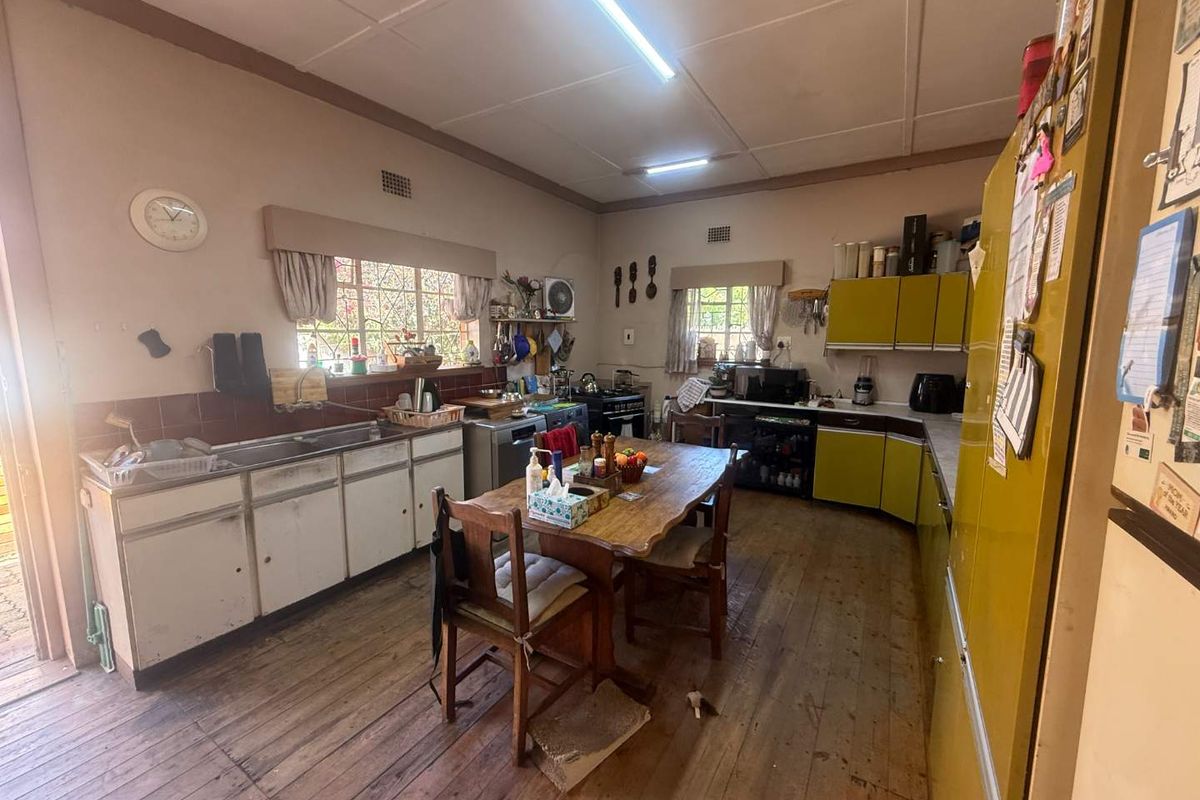 Spacious kitchen featuring timber flooring, built-in cabinetry, and a double sink, offering a functional layout with potential for modern updates.
