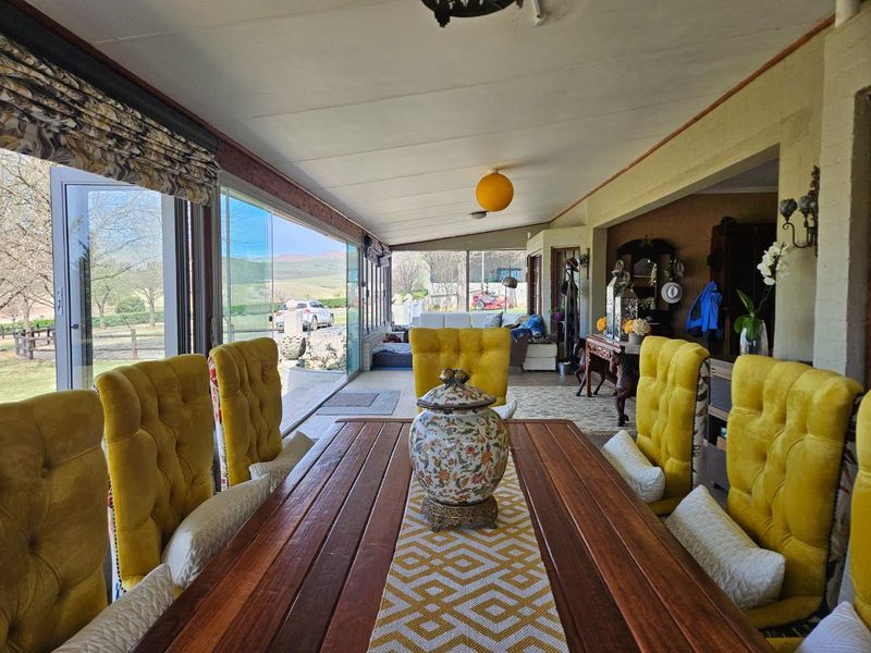 A spacious enclosed patio featuring large glass stacker doors that provide seamless indoor-outdoor flow and expansive views of the surrounding farm landscape.