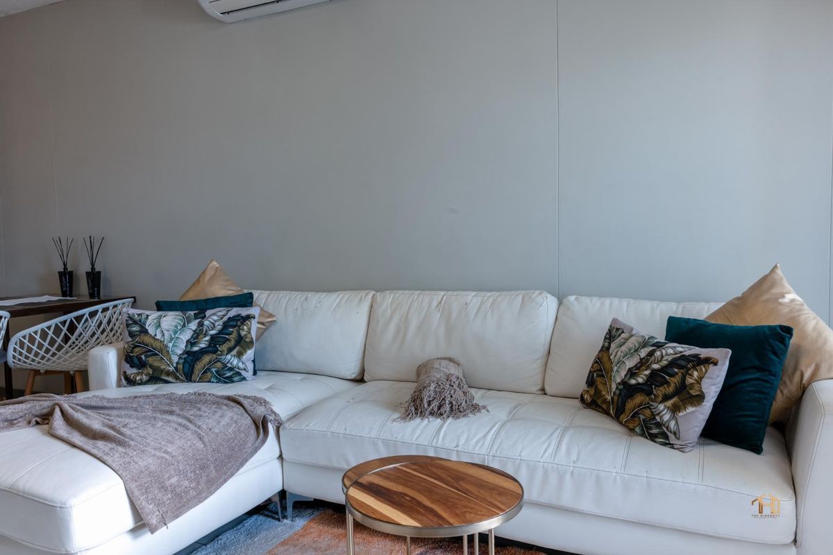 A comfortable living room featuring a wall-mounted air conditioning unit and neutral wall finishes, providing a functional and climate-controlled living space.