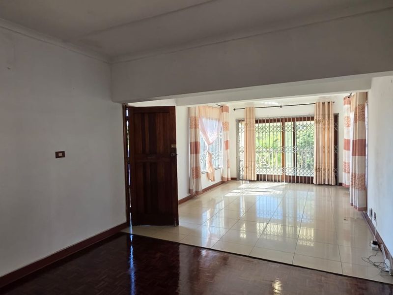 Spacious living area featuring a combination of dark parquet and light ceramic tile flooring, with large sliding glass doors leading to the exterior.