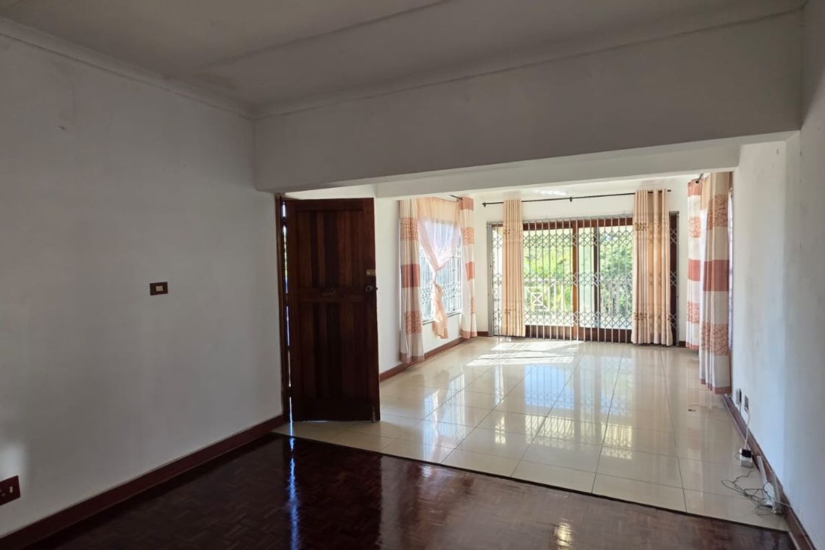 Spacious living area featuring a combination of dark parquet and light ceramic tile flooring, with large sliding glass doors leading to the exterior.