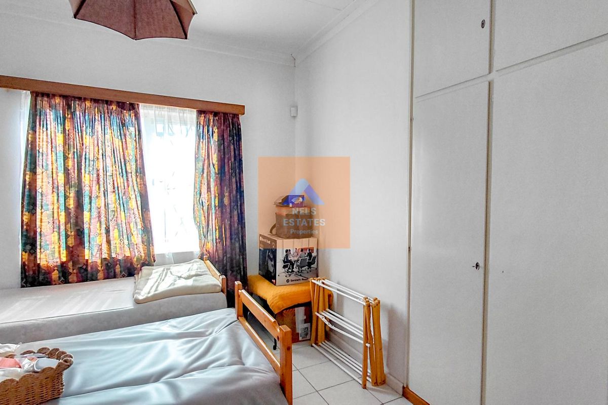 A bedroom featuring built-in cupboards and tiled flooring, offering a functional space with potential for modernization.