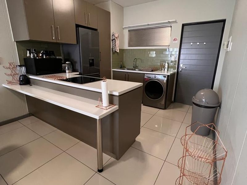 Modern kitchen featuring sleek cabinetry, stone countertops, a built-in hob, and tiled flooring, offering a functional and contemporary workspace.