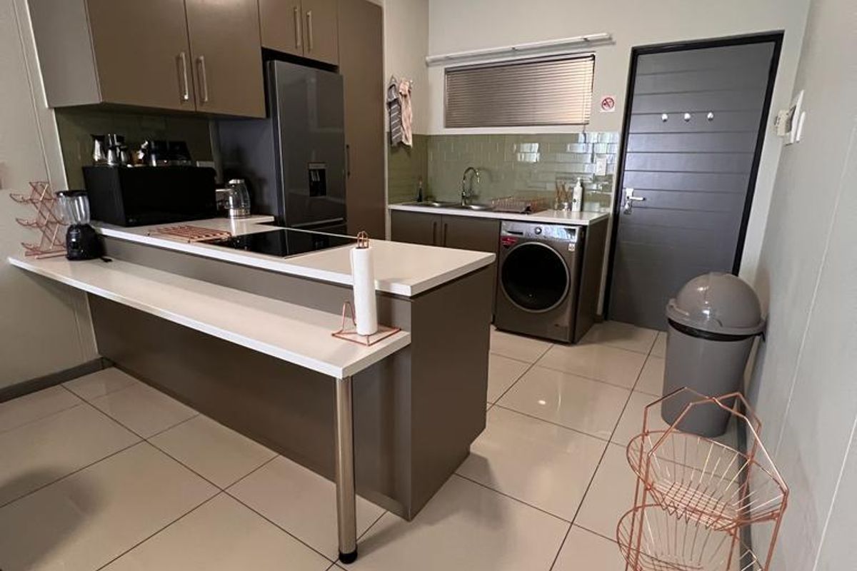 Modern kitchen featuring sleek cabinetry, stone countertops, a built-in hob, and tiled flooring, offering a functional and contemporary workspace.