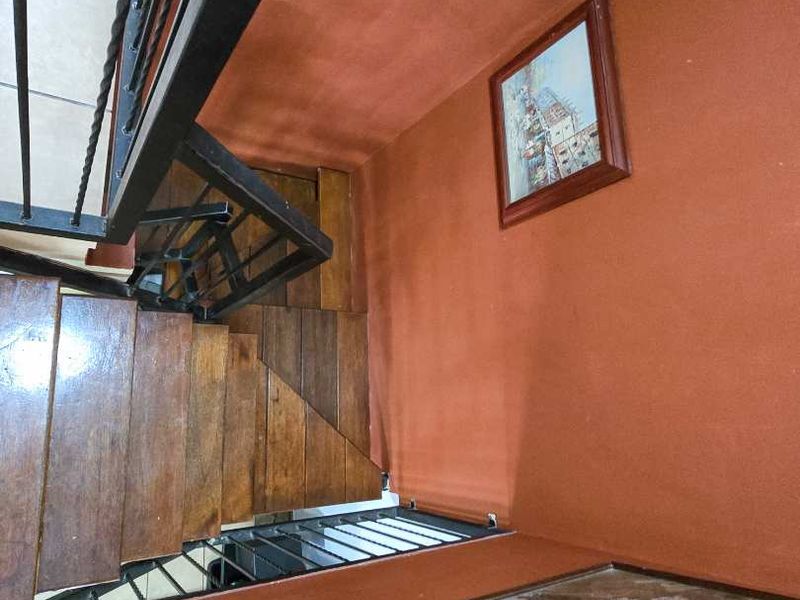 A staircase area featuring wooden treads and a black metal balustrade, finished with terracotta-toned walls.