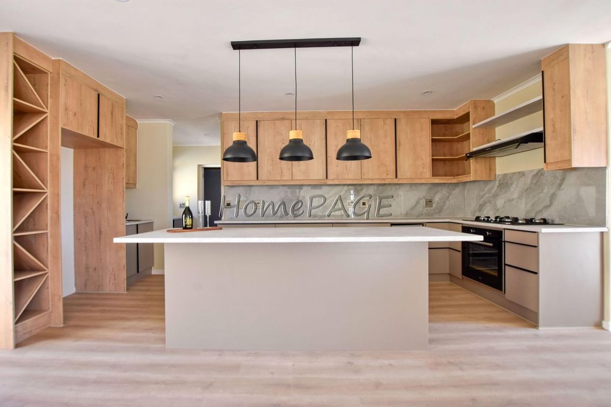 Modern kitchen featuring light wood cabinetry, a central island with stone countertop, built-in oven, gas hob, and integrated extractor fan.