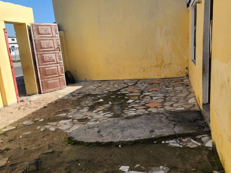 Rear outdoor area featuring a paved courtyard with boundary walls, requiring significant maintenance and repair to the paving and wall surfaces.