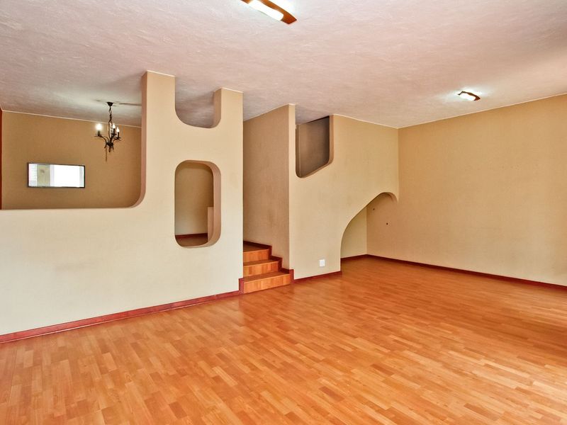 Spacious living area featuring laminate flooring, unique architectural partition walls with built-in niches, and a staircase leading to the upper level.