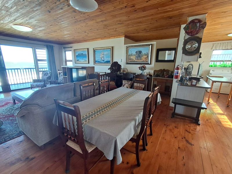 Spacious open-plan living and dining area featuring warm timber ceilings and flooring, with direct access to an outdoor balcony.