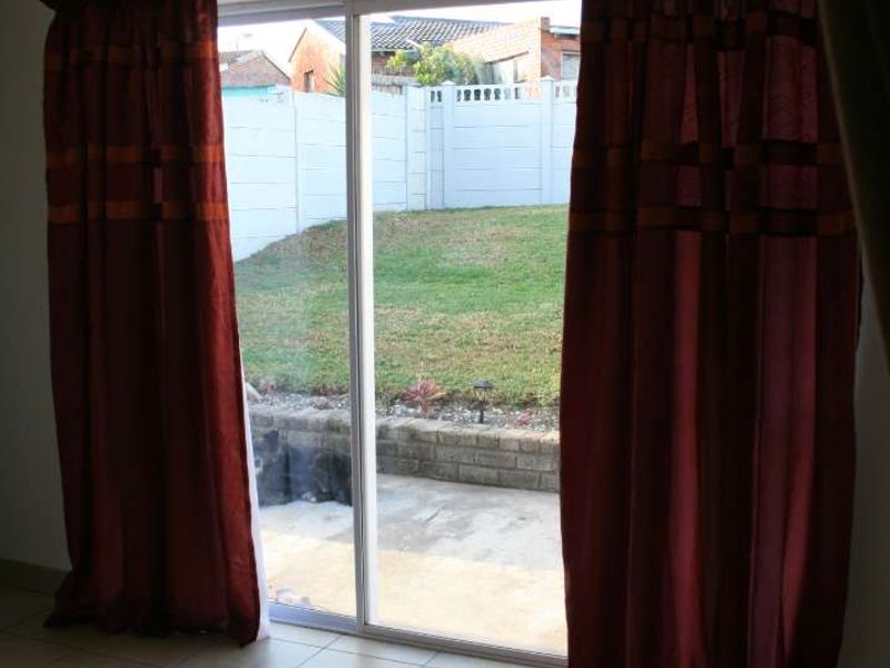 A bright living area featuring ceramic floor tiles and a sliding glass door providing direct access to the rear patio and garden.