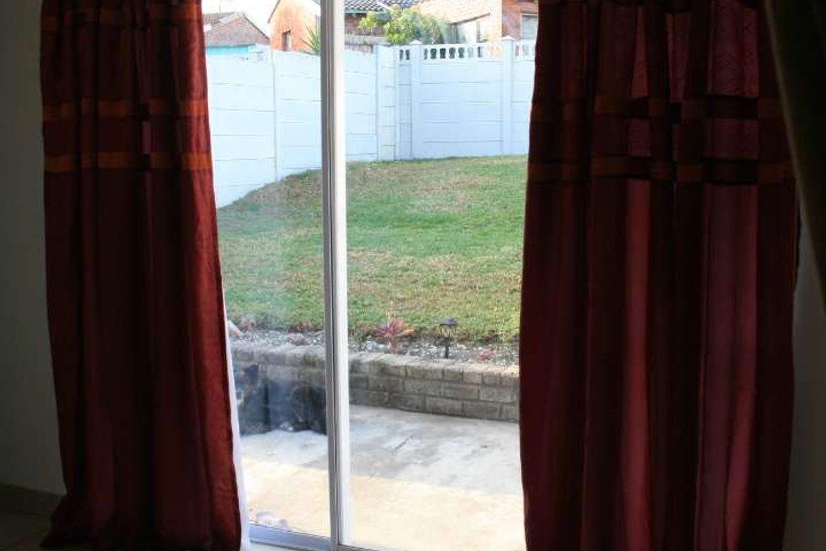 A bright living area featuring ceramic floor tiles and a sliding glass door providing direct access to the rear patio and garden.