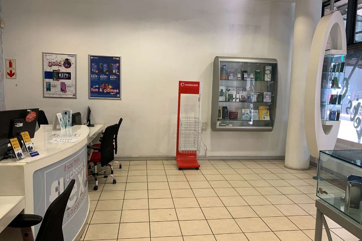 A retail store interior featuring a reception counter, tiled flooring, a structural column, and a wall-mounted display cabinet.