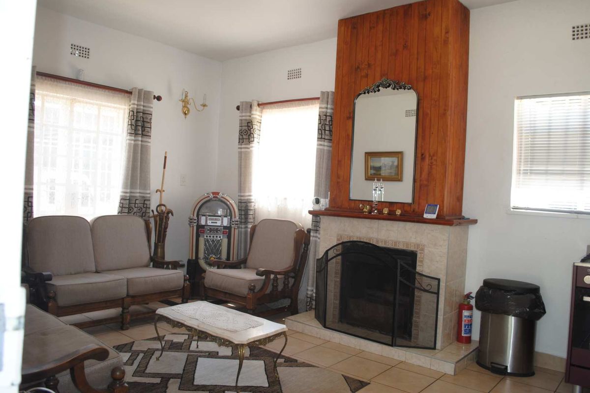 A cozy living room featuring a prominent wood-paneled fireplace with a tiled hearth and tiled flooring throughout.
