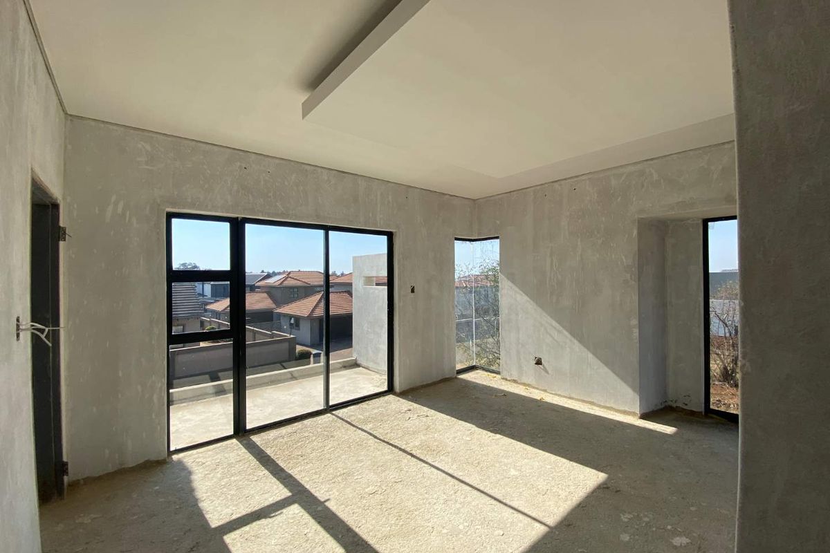 An unfinished bedroom space featuring modern black aluminium sliding doors, corner windows, and a recessed ceiling detail, awaiting final flooring and wall finishes.