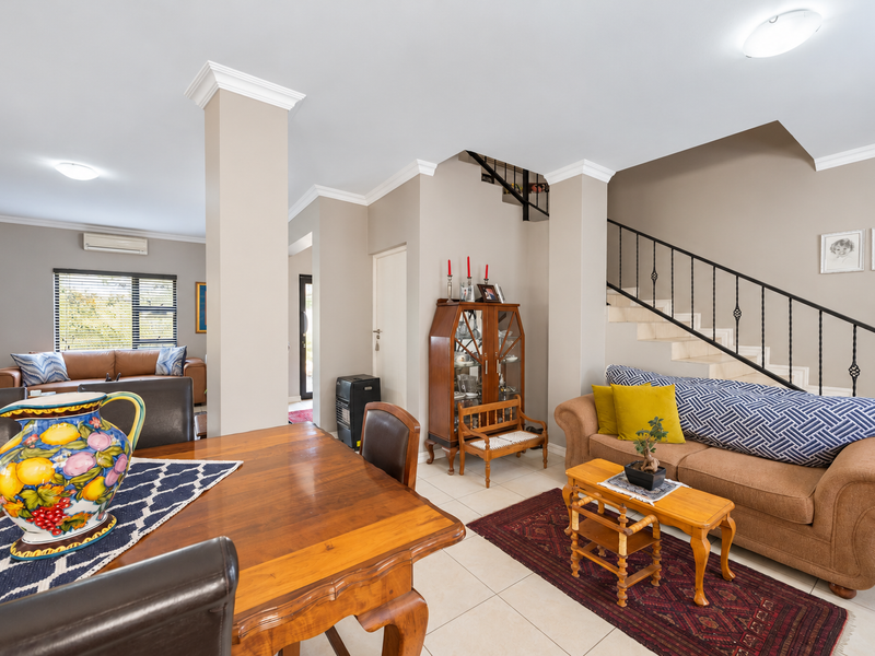 Spacious open-plan living and dining area featuring tiled floors, crown molding, and a staircase with a wrought iron balustrade.