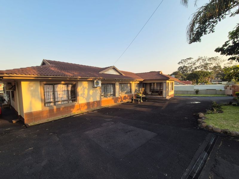 A view of the front exterior of the house featuring a tiled roof, security bars on windows, and a paved driveway.