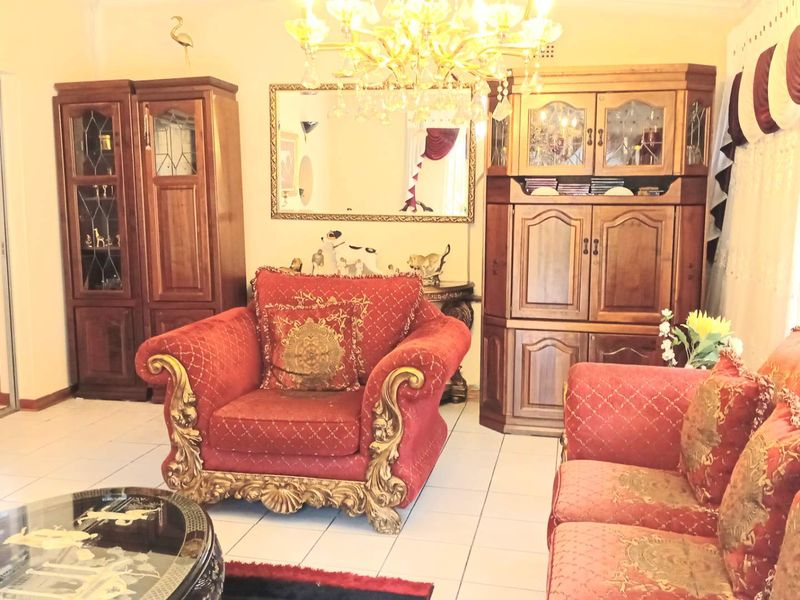 A living room featuring tiled flooring, an ornate chandelier, and built-in wooden cabinetry, offering a traditional aesthetic.