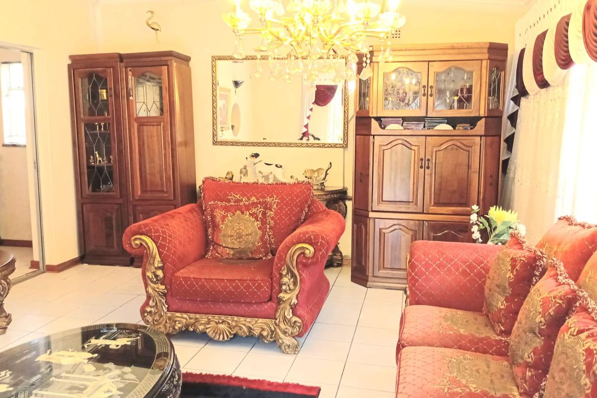 A living room featuring tiled flooring, an ornate chandelier, and built-in wooden cabinetry, offering a traditional aesthetic.