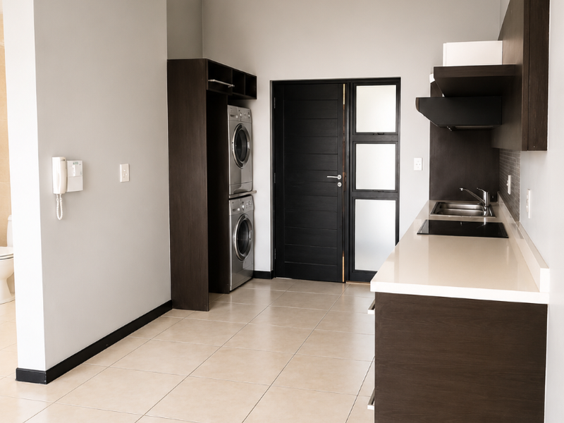 Modern kitchen featuring dark wood cabinetry, stone countertops, integrated hob, and tiled flooring, with a dedicated space for laundry appliances.
