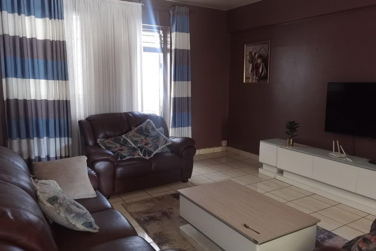 A living room featuring tiled flooring and dark-toned walls, providing a functional space for relaxation and entertainment.