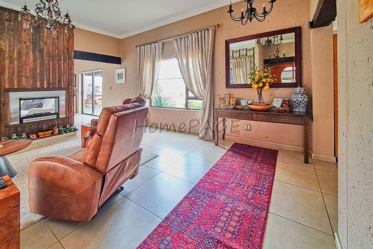 Spacious living room featuring a built-in fireplace with wood paneling, tiled flooring, and large windows allowing for natural light.
