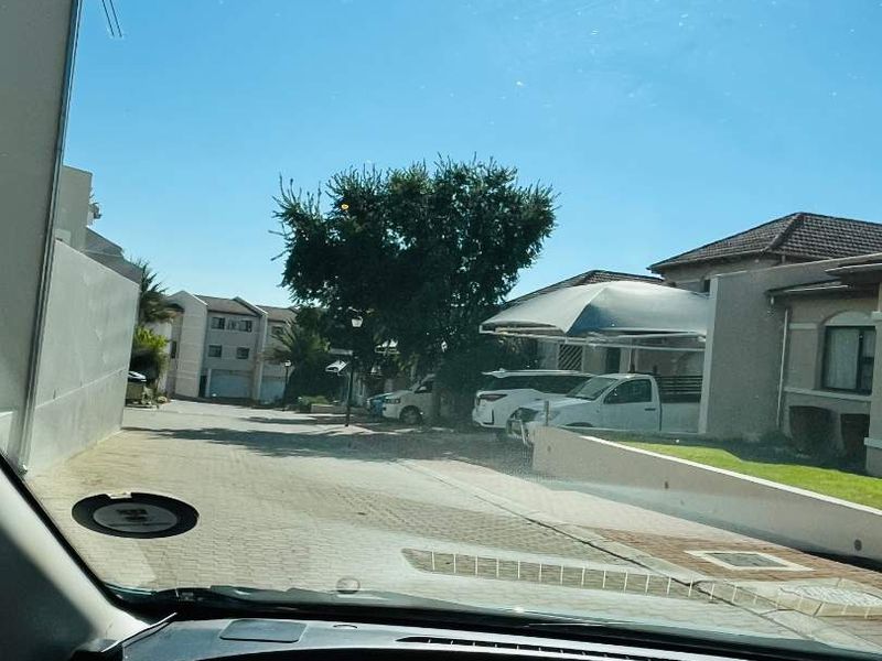 View of the townhouse complex street and driveway area, featuring paved surfaces and a covered carport structure.
