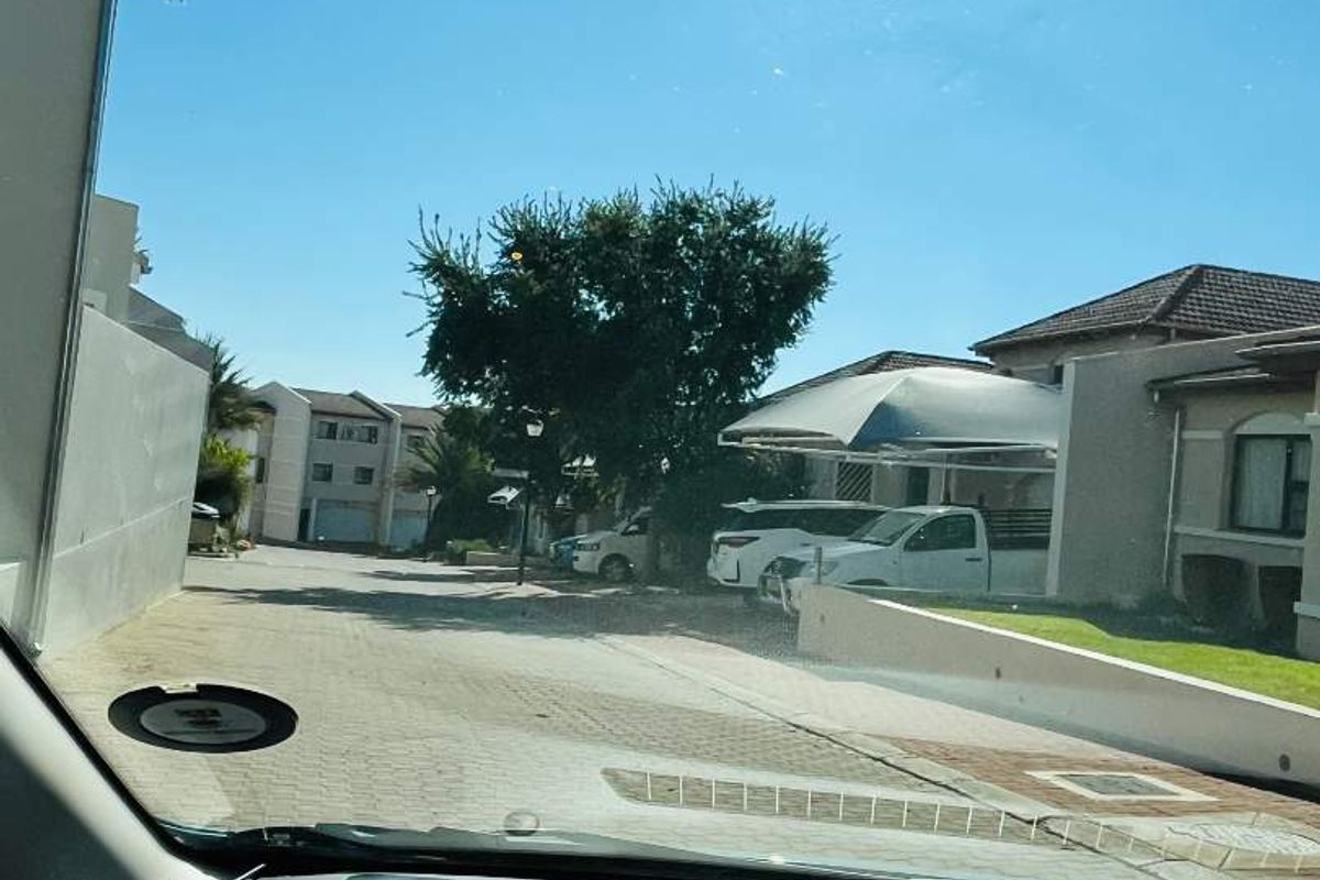 View of the townhouse complex street and driveway area, featuring paved surfaces and a covered carport structure.