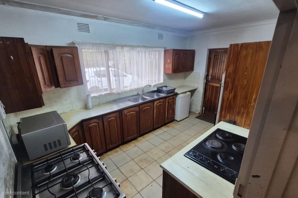 A dated kitchen featuring wooden cabinetry, dual hobs, and tiled flooring, offering significant potential for a modern renovation and aesthetic update.