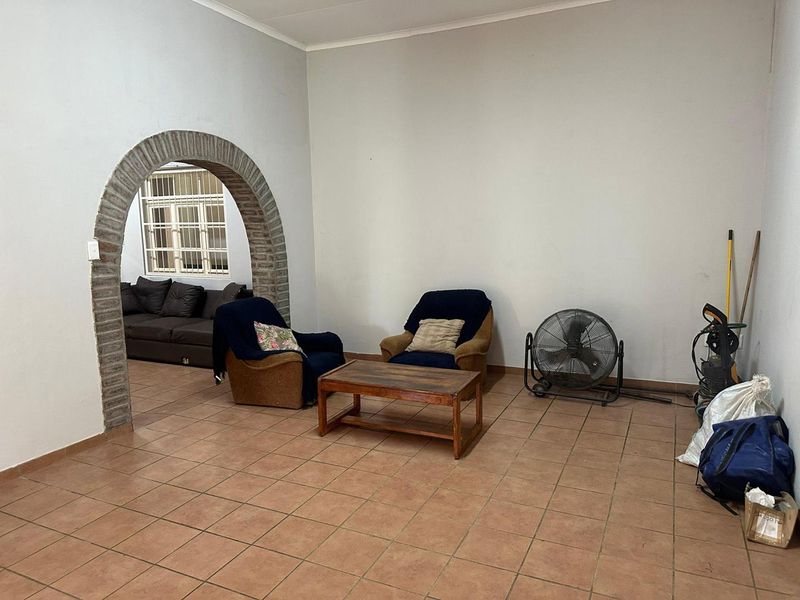 A living room featuring a distinctive brick archway leading to an adjacent space, finished with tiled flooring and neutral wall tones.