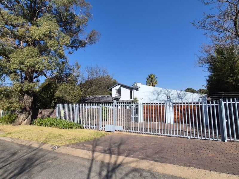 Front view of the property featuring a paved driveway, double garage with timber doors, and secure perimeter fencing.