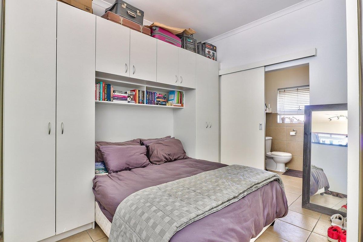 Bedroom featuring extensive built-in cabinetry with overhead storage and an adjoining en-suite bathroom with tiled finishes.