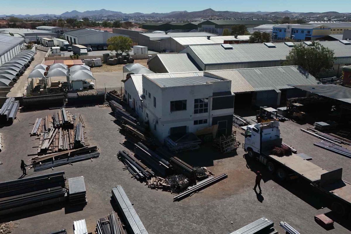 Aerial view of an industrial property featuring a warehouse building, paved yard space, and metal roofing, suitable for logistics or manufacturing operations.