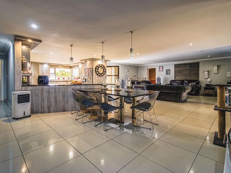 Spacious open-plan living and dining area featuring large porcelain floor tiles, modern recessed lighting, and a central kitchen island with integrated cabinetry.