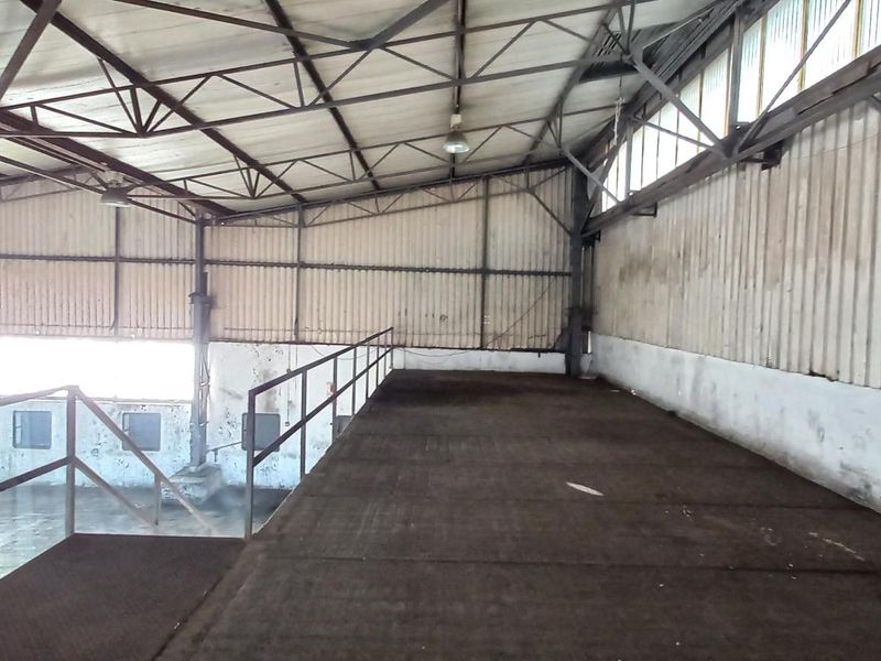 An industrial mezzanine level featuring a metal structure, steel railings, and corrugated wall cladding, suitable for storage or additional workspace.