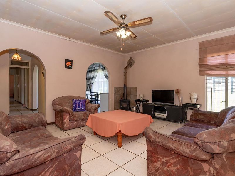 Living room featuring tiled flooring, a wood-burning fireplace, and arched doorways leading to adjacent spaces. The ceiling shows signs of water staining.