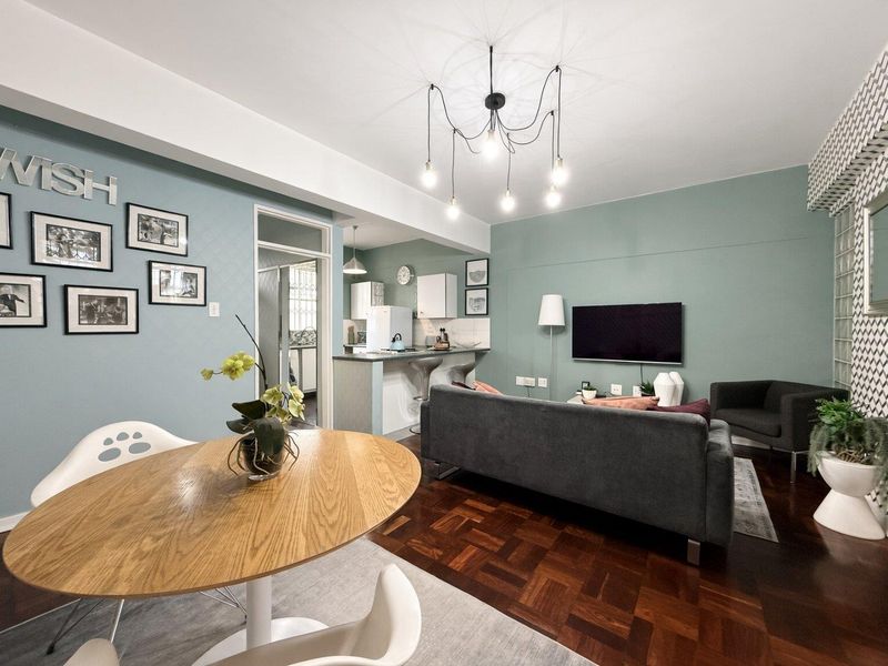 Open-plan living and dining area featuring rich parquet flooring, a breakfast counter, and modern pendant lighting, seamlessly connected to the kitchen.