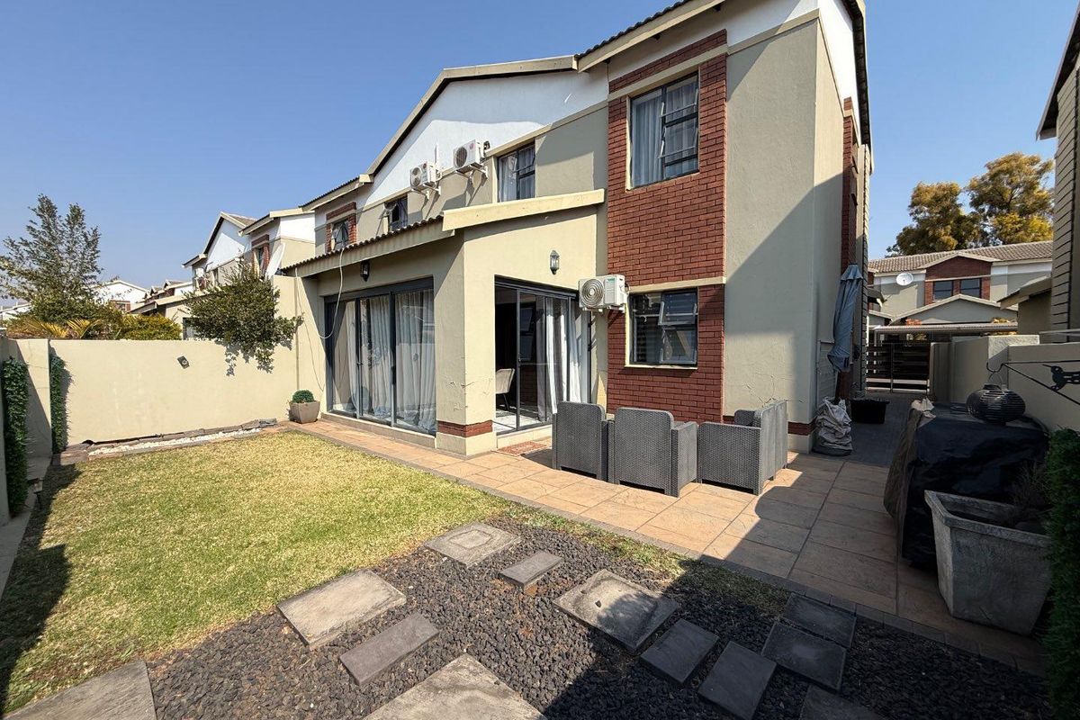 Rear view of the townhouse featuring a paved patio area, sliding glass doors, and a private garden space.