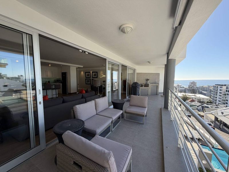 Spacious covered balcony featuring tiled flooring, a built-in outdoor counter, and metal balustrades, offering seamless indoor-outdoor flow and expansive coastal views.