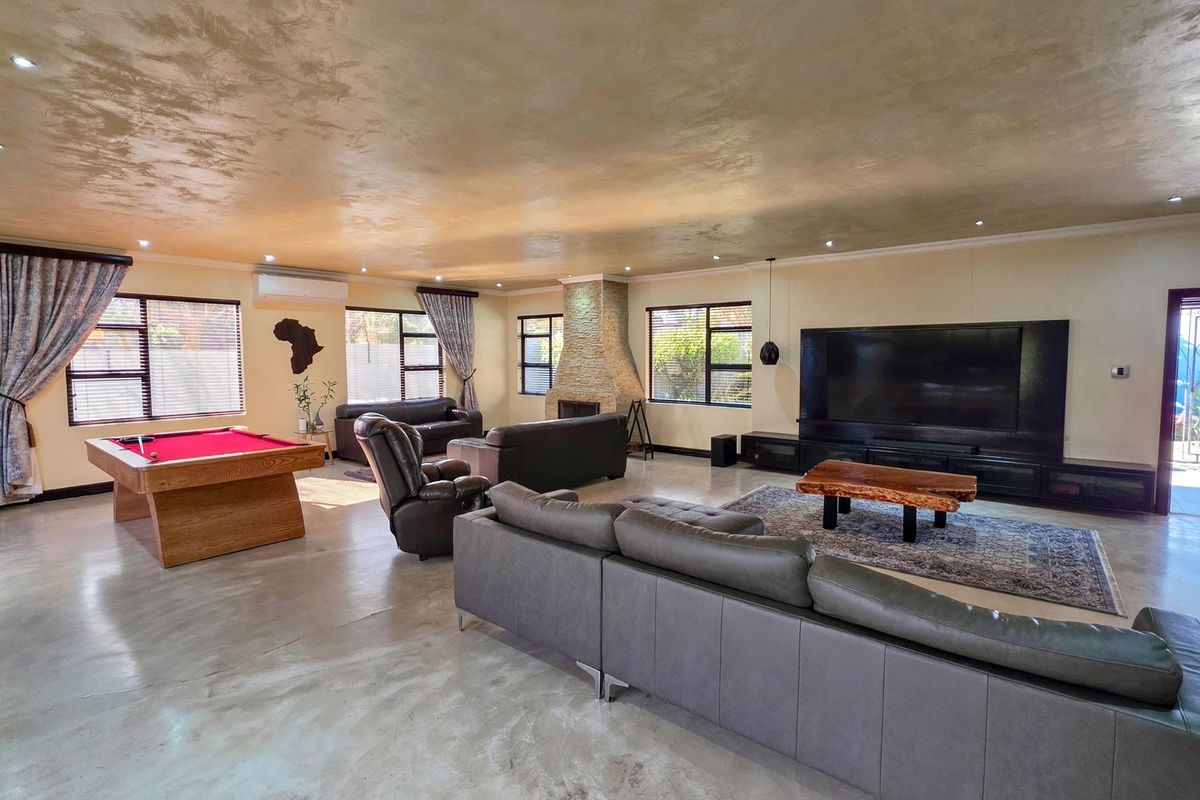Spacious open-plan living area featuring polished concrete floors, a prominent stone-clad fireplace, and recessed lighting, offering a versatile layout for relaxation and entertainment.